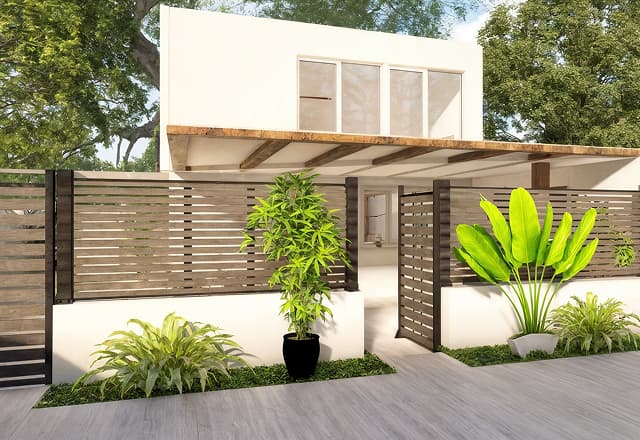 Fachada de vivienda reformada con valla de madera moderna y plantas tropicales en la entrada